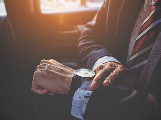Businessman looking at the time on his wrist watch in car. Business concept.